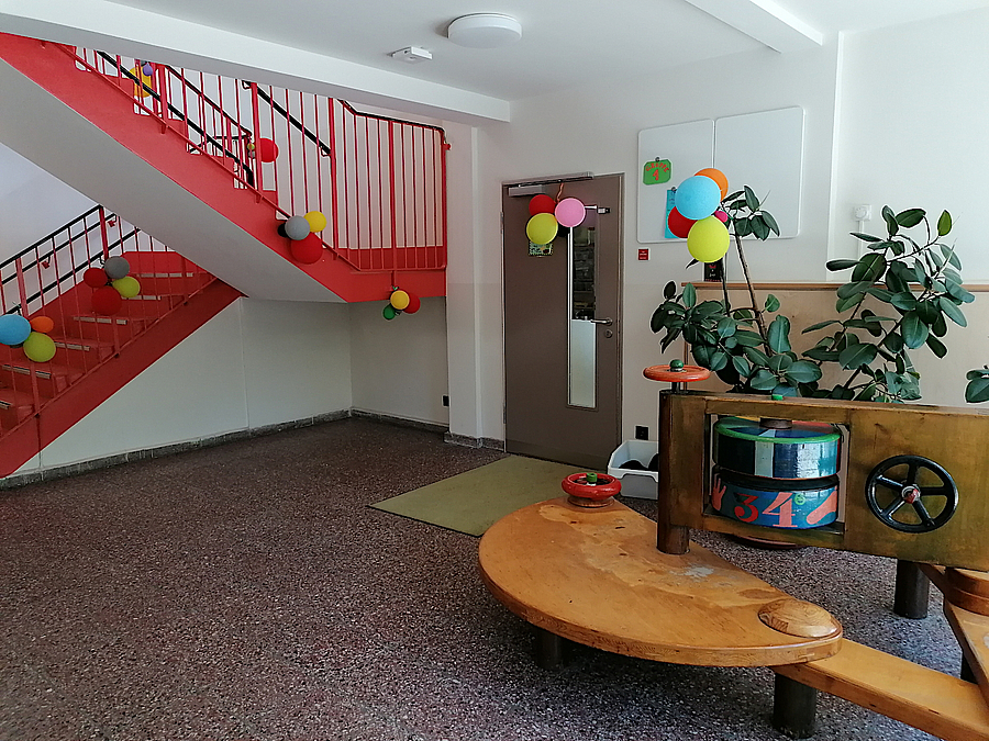 Raum mit runder Holzbank und roter Treppe