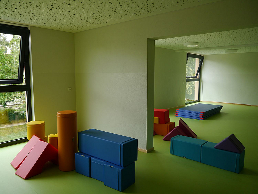 Grün gehaltene Räume mit farbigen Schaumstoffkörpern auf dem Boden, große Fenster