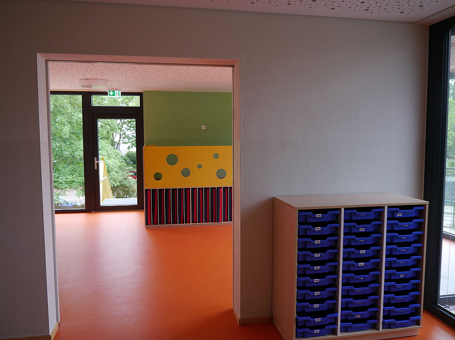 Blick durch mehrere Räume mit blauen und gelben Möbeln, orangefarbenem Boden