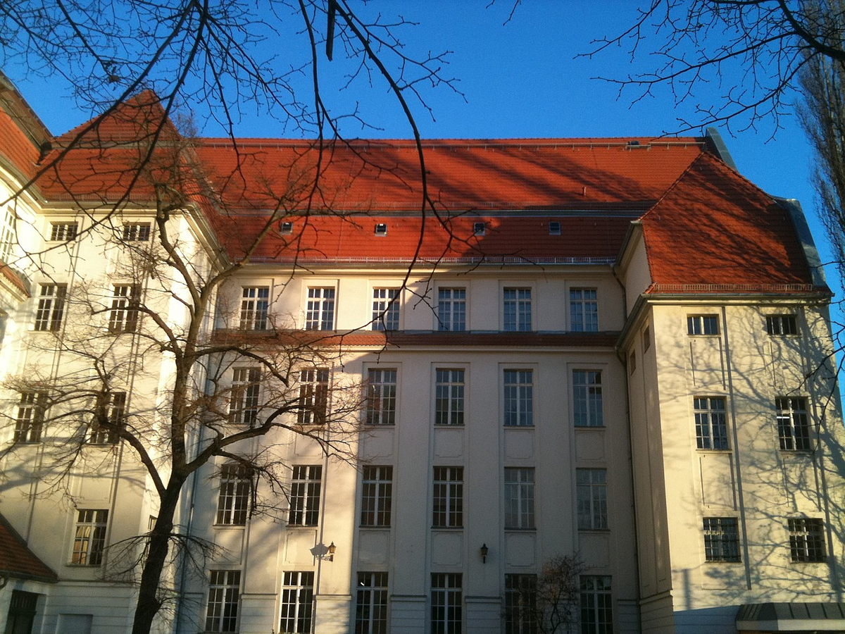 Hohe, hellgelbe Fassade eines historischen Schulgebäudes