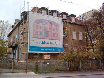 Sanierungsbedürftiges Gebäude mit Gerüst und Schild "Ein Schloss für alle!"