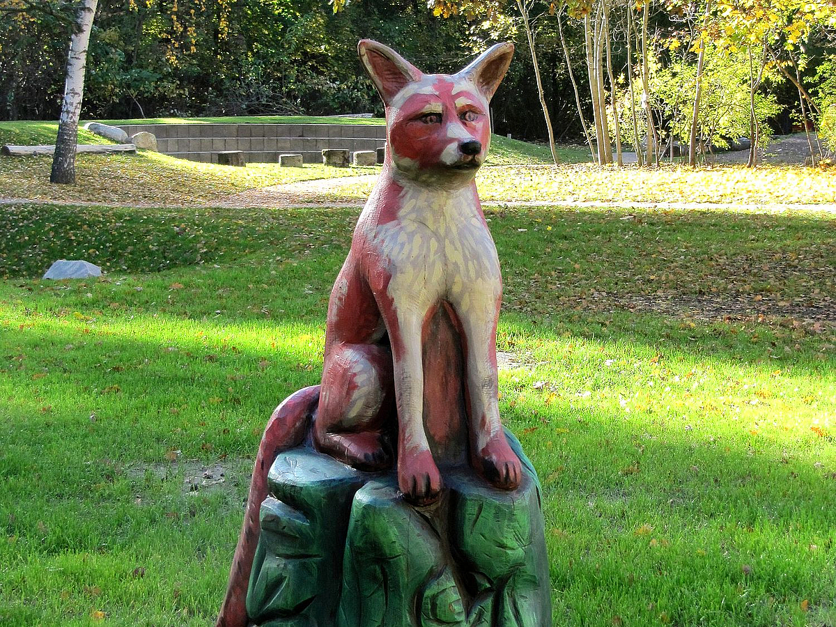 Fuchsfigur aus Holz auf Rasen, Amphitheater, Gehölze