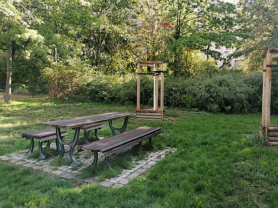 Picknickplatz mit Tisch, zwei Bänken und Jungbäumen