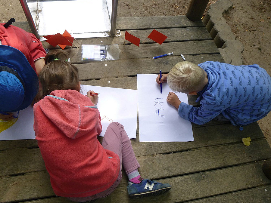 Kinder knien auf Rutschenturm und zeichnen, Fähnchen