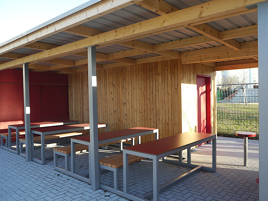 Offener Pavillon aus Holz mit Tischen und Bänken im Rot
