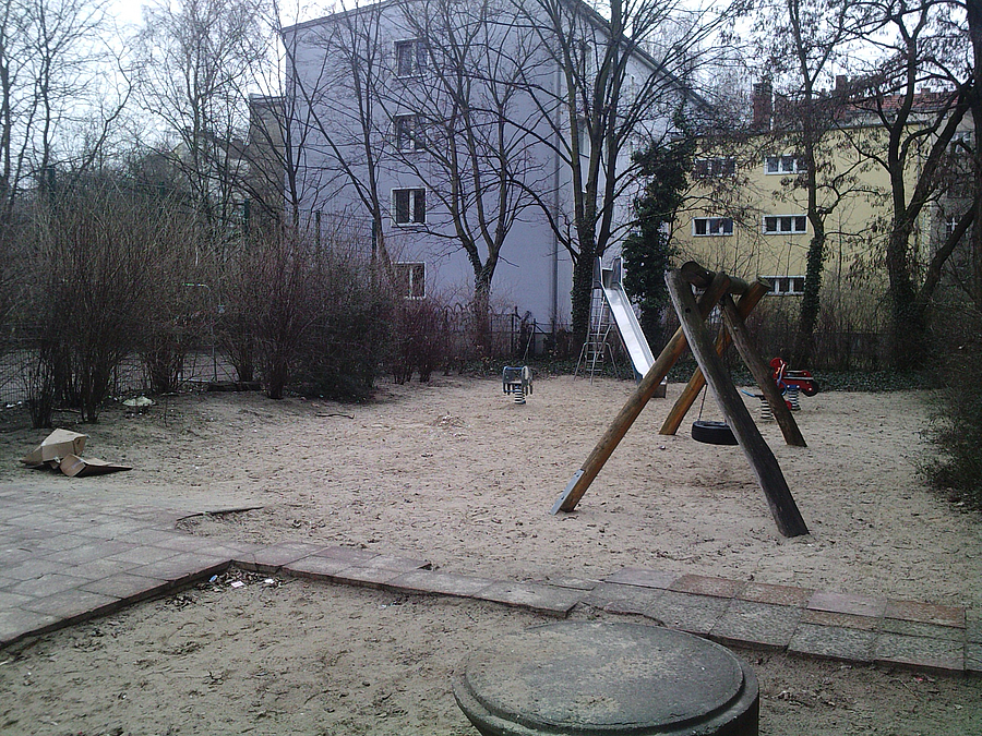 Spielplatz im Winter mit Müll, kaputtem Gehweg und teilweise alten Spielgeräten