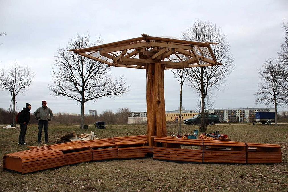 Hölzernes Schirmartiges Objekt mit nicht fertig aufgebauten Holzbänken