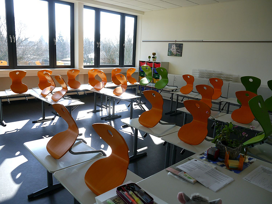 gelbe und grüne Stühle auf Tischen im Klassenraum