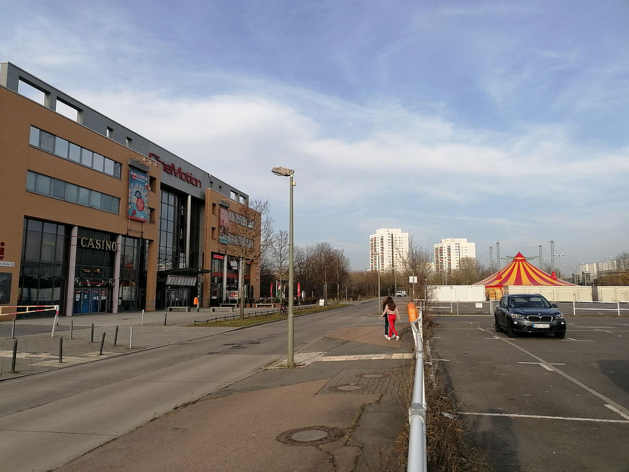 Modernes Kino, fast leerer Parkplatz, im Hintergrund Hochhäuser und Zirkuszelt