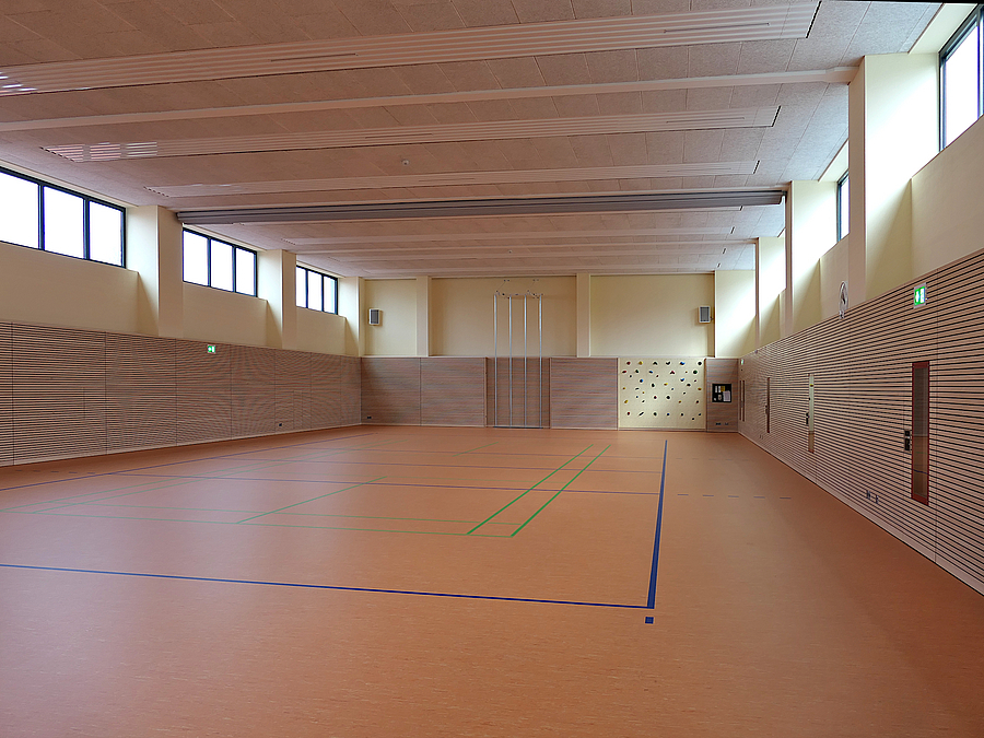 Sporthalle mit rötlichem Boden und Holzlamellenwänden