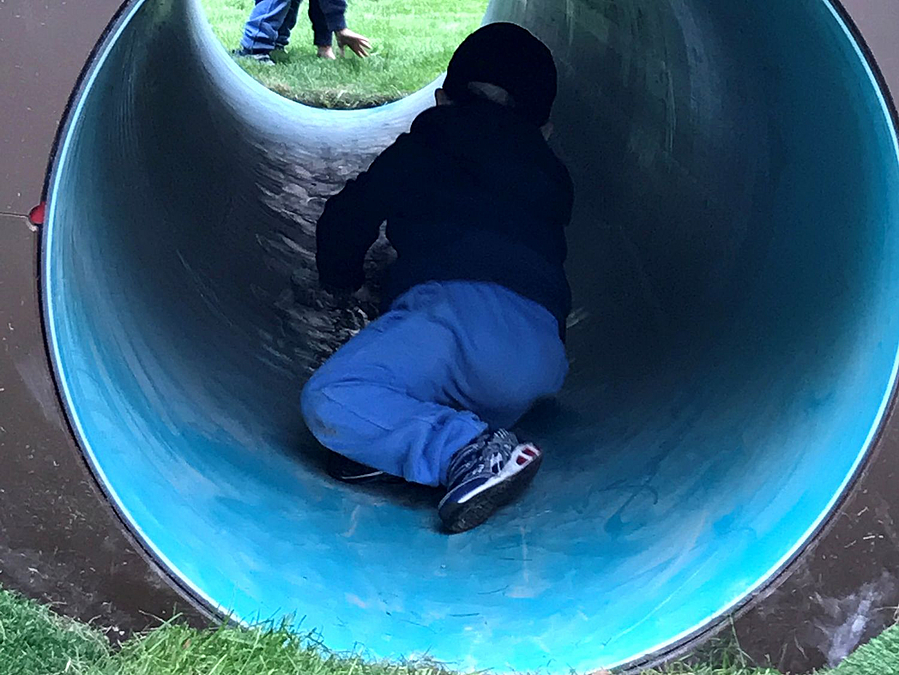 Kind kriecht in blauer Tunnelröhre