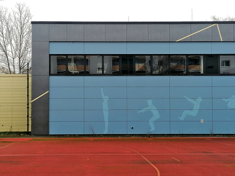 Blaue Sporthallenfassade mit helleren Umrissen von Sporttreibenden