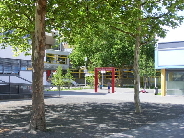 Platz unter Platanen, rotes, rechteckiges Tor, Schulgebäude